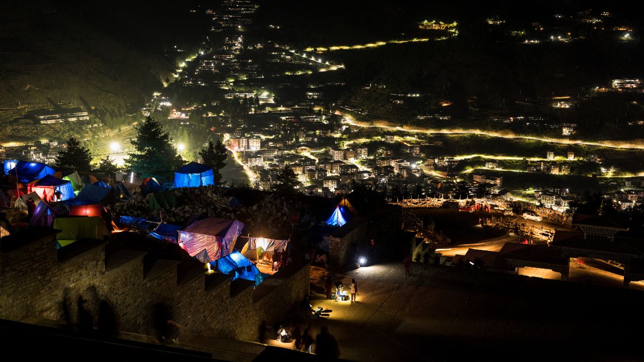 Views of Thimphu city at night, showcasing city lights, streets, and surrounding hills.