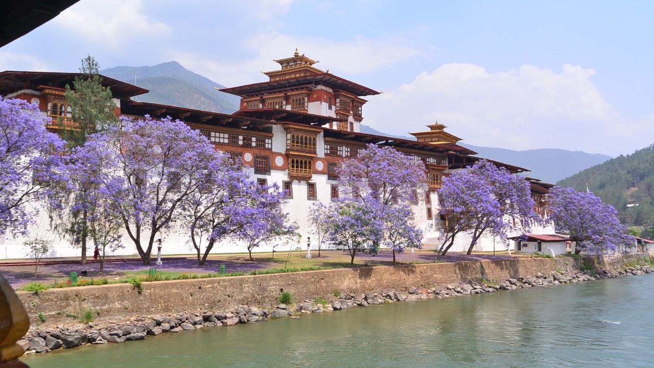 Scenic riverside view of Punakha Dzong surrounded by lush valleys and mountains in Bhutan