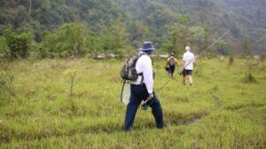 Hikers walking along a grassy trail in the Bhutan mountains.