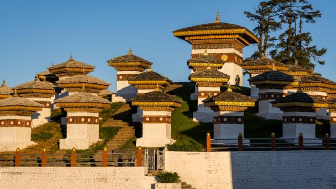 Dochula Pass chortens with traditional Bhutanese stupas set against a clear blue sky.