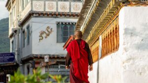 Bhutanese monk walking along a monastery wall in Paro town.