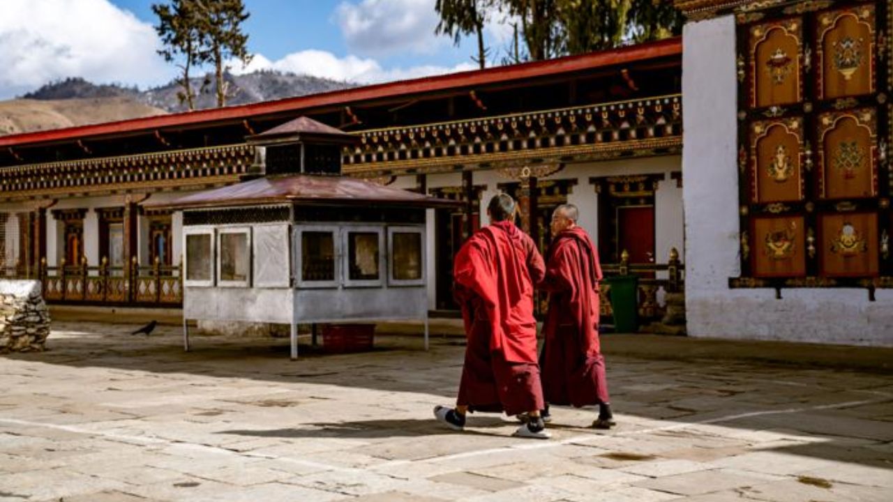 Monks in traditional red robes walking along a quiet path in Phobjikha Valley